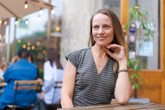 Retrato de mulher caucasiana sentada na cadeira no café em um sorriso emocional feliz