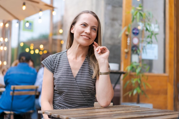 Retrato de mulher caucasiana sentada na cadeira no café em um sorriso emocional feliz