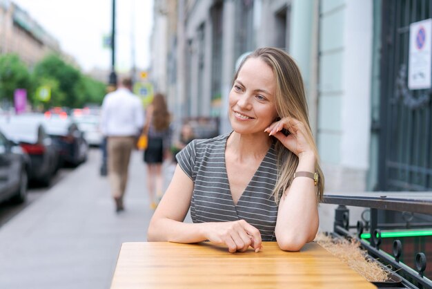 Retrato de mulher caucasiana sentada na cadeira no café em um sorriso emocional feliz