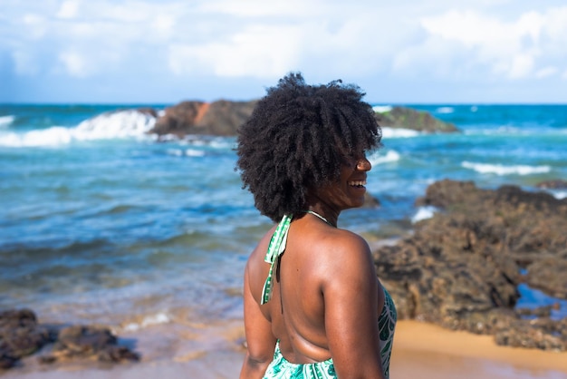 Foto retrato de mulher com cabelo black power olhando o mar ao fundo o céu balança e o mar praia do rio vermelho salvador brasil