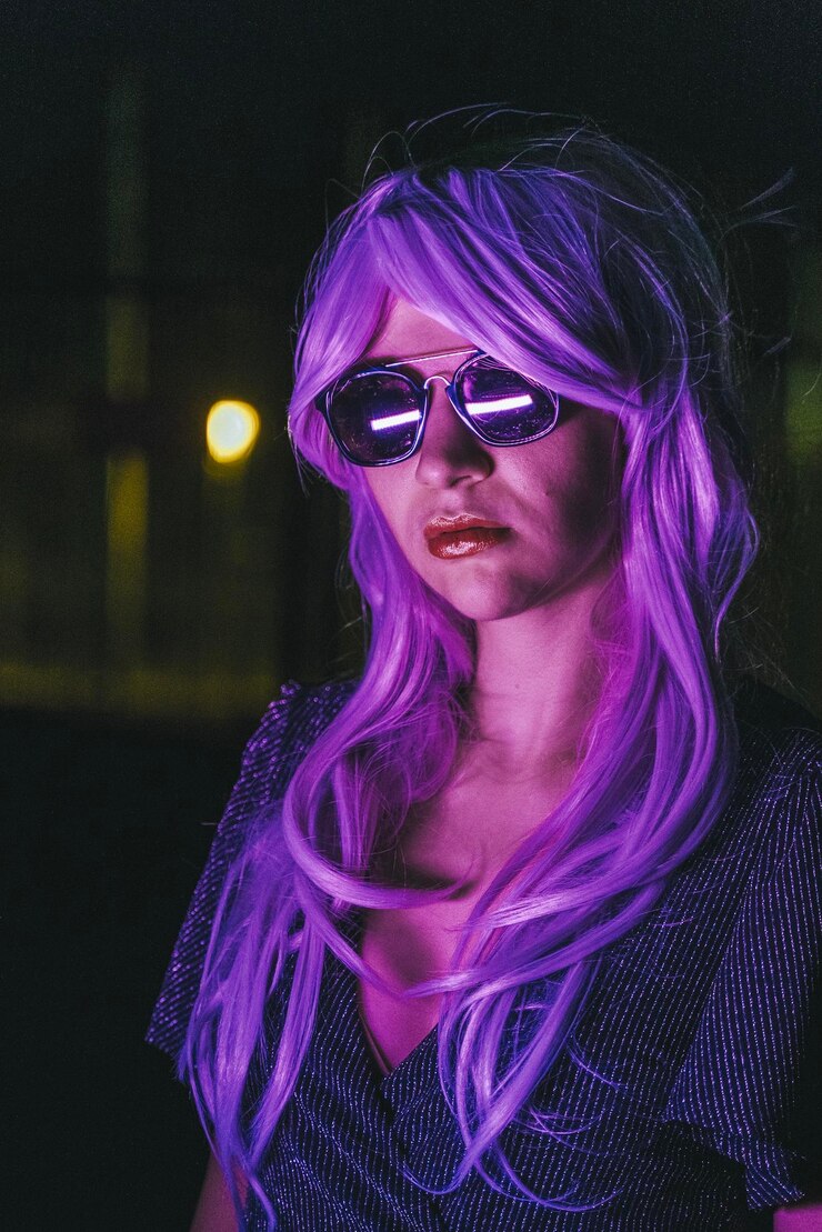 Foto retrato de mulher com cabelo tingido usando óculos de sol à noite
