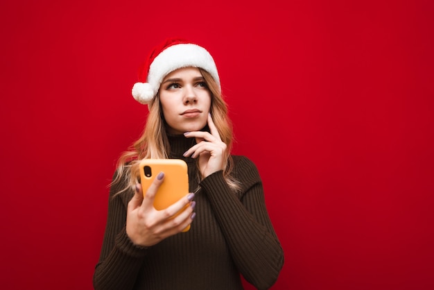 retrato de mulher com chapéu de Papai Noel com telefone