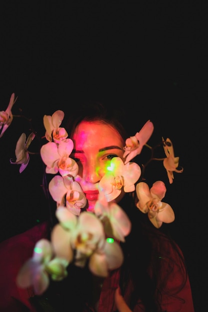 Retrato de mulher com flores cor-de-rosa contra fundo preto