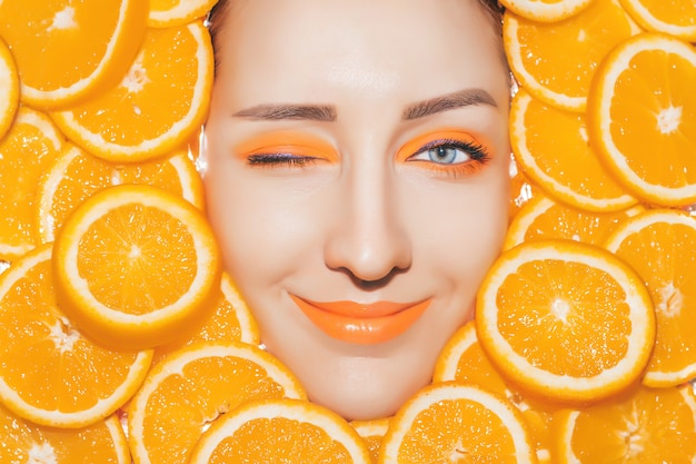 Retrato de mulher com laranjas closeup. Maquiagem laranja brilhante
