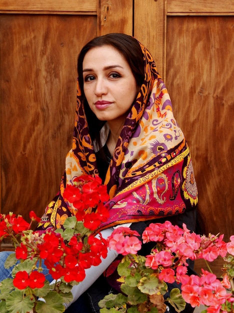Foto retrato de mulher com lenço de cabeça com flores contra madeira