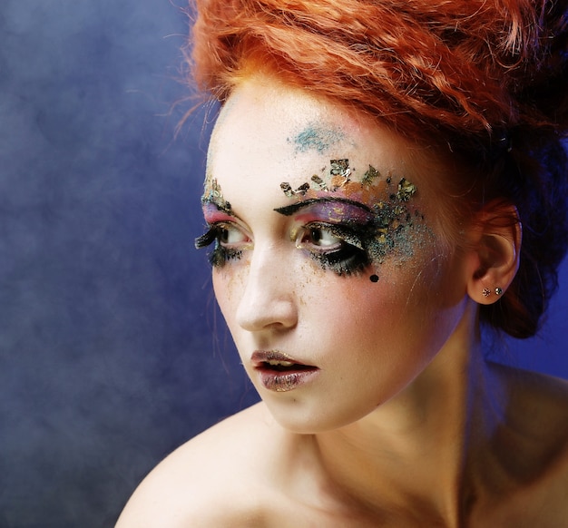 Retrato de mulher com maquiagem artística sobre fundo de fumaça