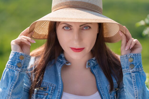 Retrato de mulher com olhos cinzentos olhando para a câmera no fundo natural verde turva da floresta