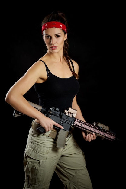 Foto retrato de mulher com rifle de pé contra fundo preto