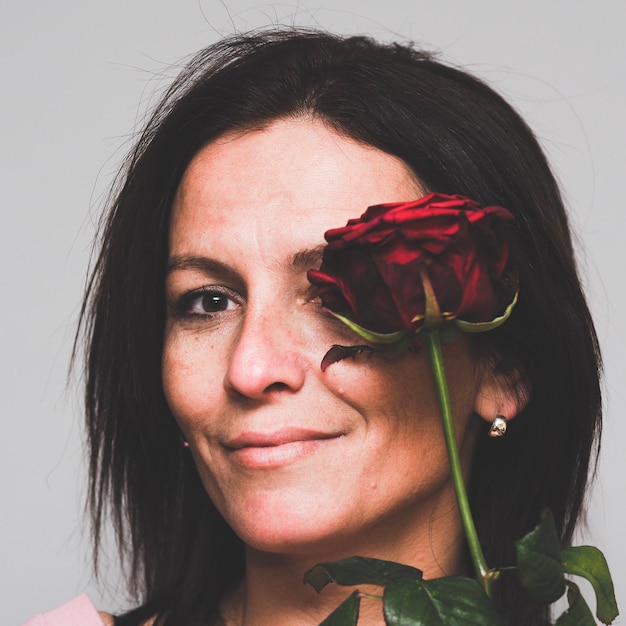 Foto retrato de mulher com rosa contra fundo branco