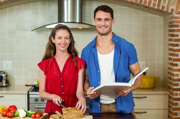 Retrato, de, mulher, corte, loaf pão, enquanto, homem, verificar, a, receita, livro, em, cozinha, casa