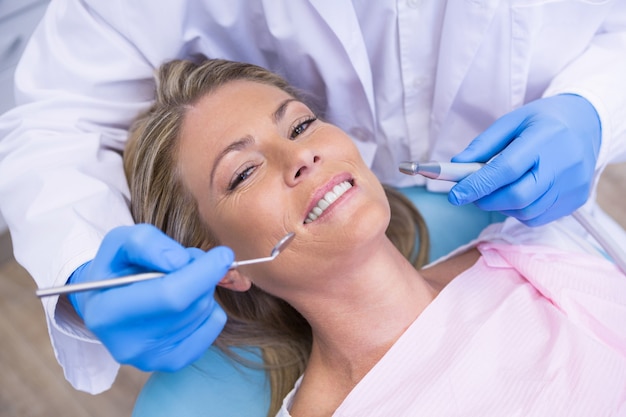 Retrato de mulher de alto ângulo por ferramenta de dentista de dentista