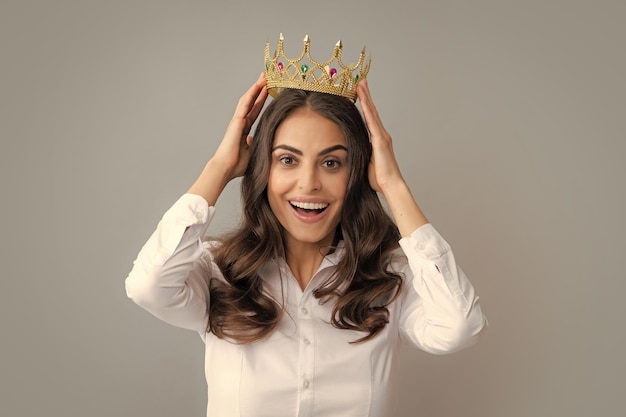 Retrato de mulher de arrogância com coroa dourada na liderança e sucesso da cabeça Atraente rica garota arrogante usando coroa isolada sobre fundo cinza