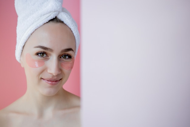 Retrato de mulher de beleza com tapa-olhos no fundo rosa. Rosto de beleza de mulher com máscara sob os olhos. Cuidados com a pele, conceito de produto cosmético com espaço de cópia