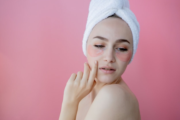 Retrato de mulher de beleza com tapa-olhos no fundo rosa. Rosto de beleza de mulher com máscara sob os olhos. Cuidados com a pele, conceito de produto cosmético