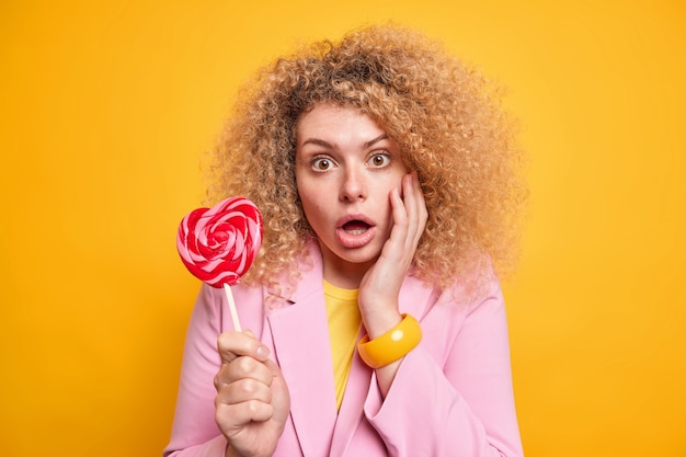 Retrato de mulher de cabelo encaracolado olhando maravilhado para a câmera