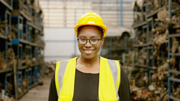 Retrato de mulher de engenharia africana americana está trabalhando em uma fábrica de peças de motor de planta industrial pesada.