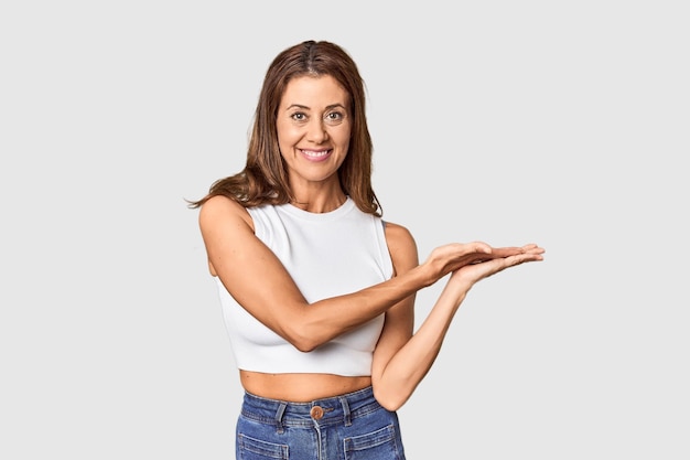 Foto retrato de mulher de meia idade em estúdio, segurando um espaço de cópia na palma da mão