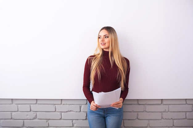 Retrato de mulher de mulher de negócios jovem feliz perto na parede branca.