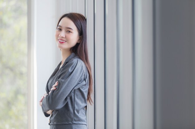 Retrato de mulher de negócios asiáticos que tem cabelos longos e braços cruzados no local de trabalho.