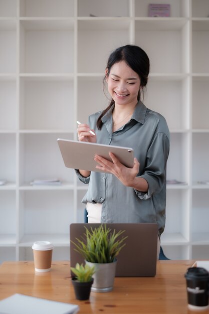 Retrato de mulher de negócios asiáticos trabalhando com tablet no escritório