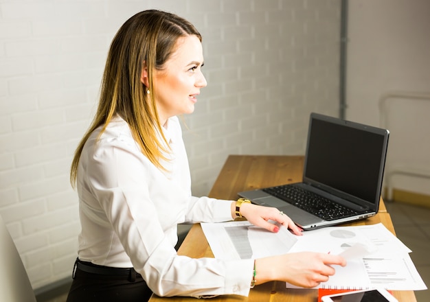 Retrato de mulher de negócios bem sucedido, trabalhando com o laptop no escritório