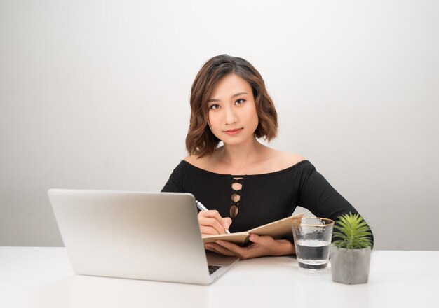 Retrato de mulher de negócios com laptop escreve em um documento em seu escritório