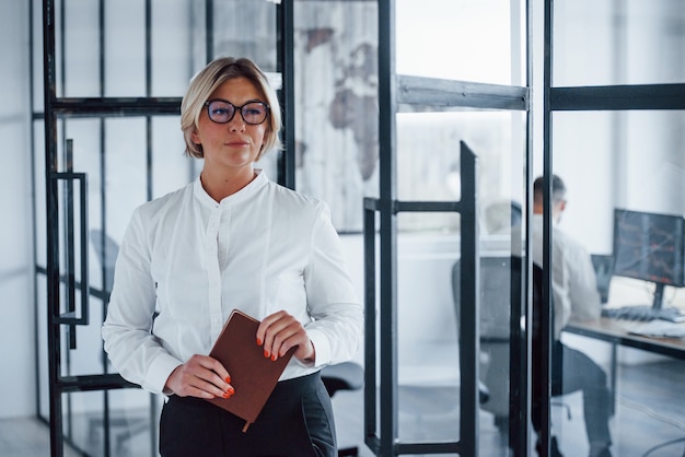 Retrato de mulher de negócios com roupas formais, que fica no escritório.