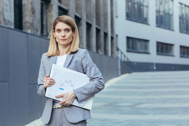 Retrato de mulher de negócios de terno cinza fora empresária de escritório com laptop e documentos em papel