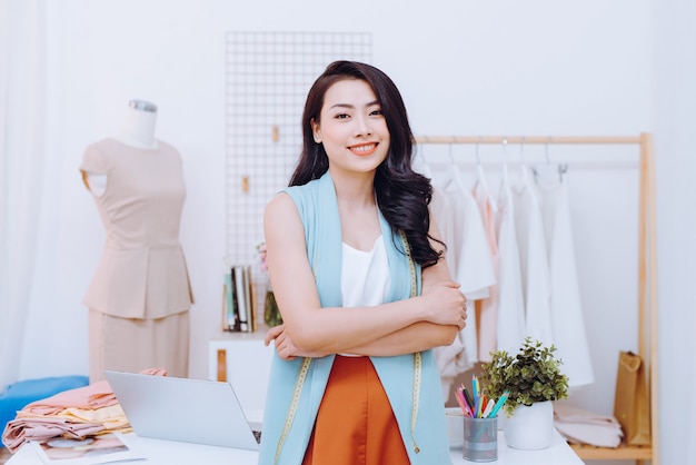 Retrato de mulher de negócios feliz designer de moda asiática no estúdio. Sorrindo, em pé, olhando para a câmera.