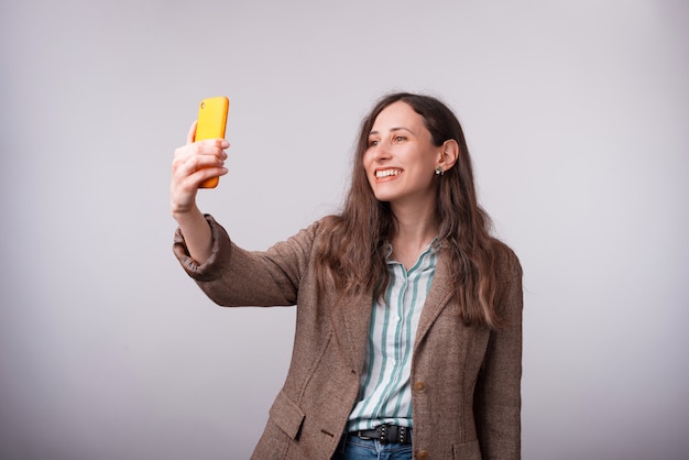 Retrato de mulher de negócios jovem encantadora tomando selfie com smartphone.