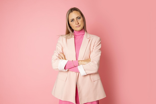 Retrato de mulher de negócios posando para a câmera com os braços cruzados em fundo rosa, olhando para a câmera, terno busto, conceito de empresário, professora.