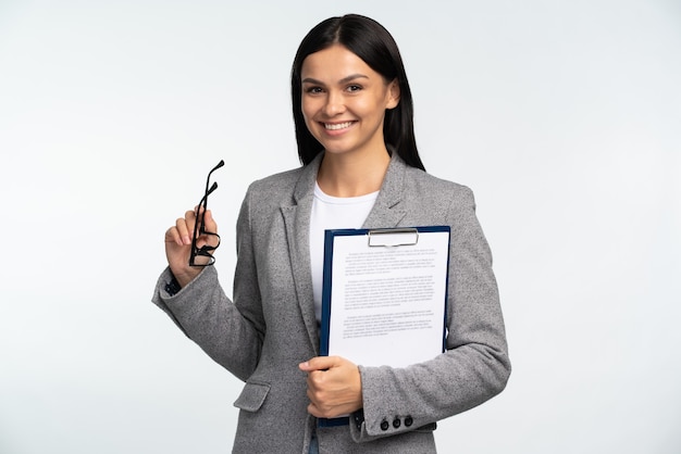 Retrato de mulher de negócios sorridente com pasta de papel, segurando os óculos e sorrindo isolado sobre o fundo branco. conceito de ocupação