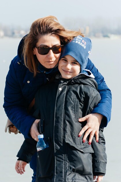 Foto retrato de mulher de óculos de sol com filho contra o lago