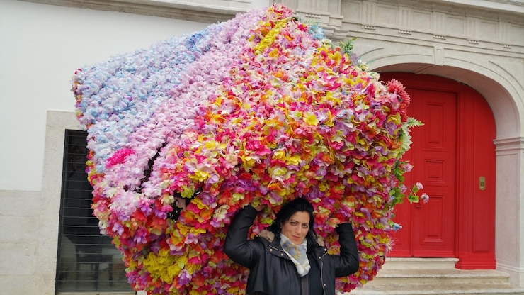Foto retrato de mulher de pé junto a arranjos florais contra o edifício