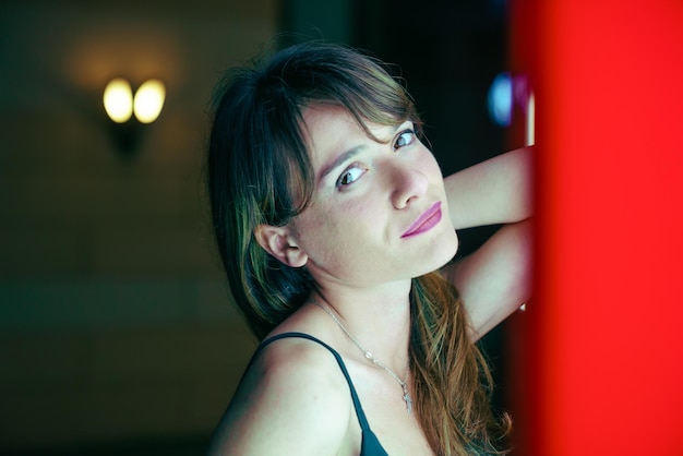 Retrato de mulher de pé junto à parede vermelha