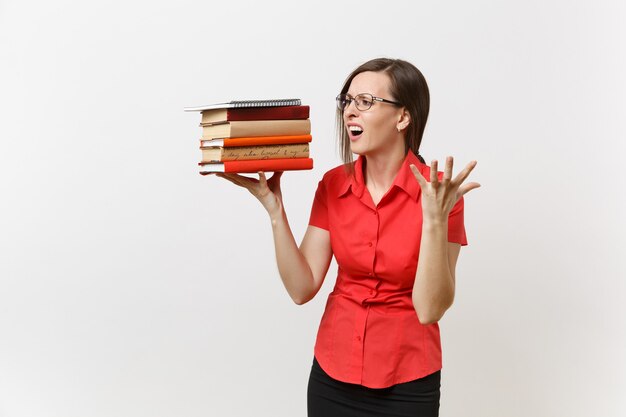 Retrato de mulher de professor de negócios chateado frustrado cansado em óculos de camisa vermelha, segurando a pilha de livros de texto nas mãos, isolados no fundo branco. educação ou ensino no conceito de universidade do ensino médio.