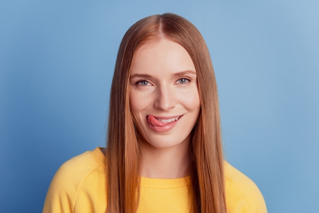 Retrato de mulher de sonho coquete e glamourosa protuberante língua lambendo os lábios em fundo azul