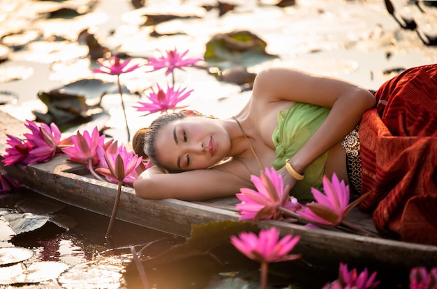 Foto retrato de mulher deitada em plantas de flores rosas