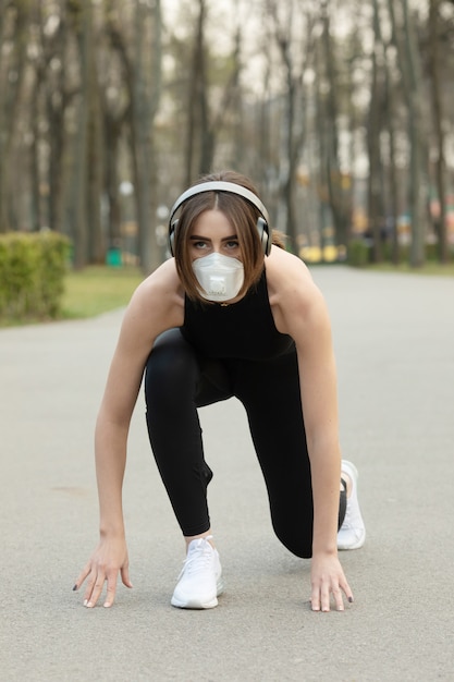 Retrato de mulher desportiva caucasiana, vestindo uma máscara protetora de proteção médica enquanto corre no parque. o vírus corona ou o covid-19 está se espalhando por todo o mundo.