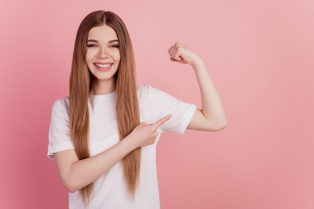 Retrato de mulher desportiva com dedo direto mostrando sorriso dentuço de bíceps