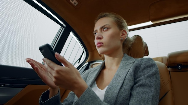 Retrato de mulher digitando carta no telefone no carro de luxo Menina pensando no veículo