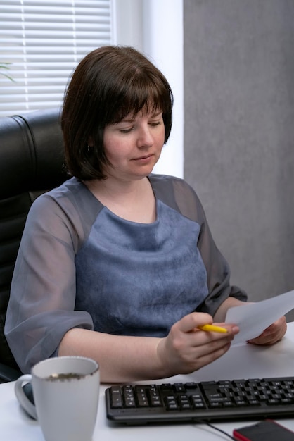 Retrato de mulher diretora de empresa em escritório privado durante trabalhos com papéis. Moldura vertical