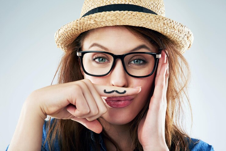 Foto retrato de mulher e dedo com bigode em estúdio para atitude peculiar e engraçada com óculos hipster feminina cômica e criativa em fundo branco para comédia goofy e moda moderna ou elegante