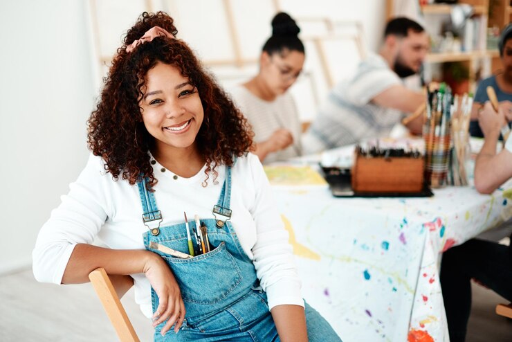Foto retrato de mulher e feliz em estúdio de arte para pintura e criatividade ou talento e grupo em oficina artista feminina gen z e rosto com sorriso para acrílico ou design com pincéis e amigos