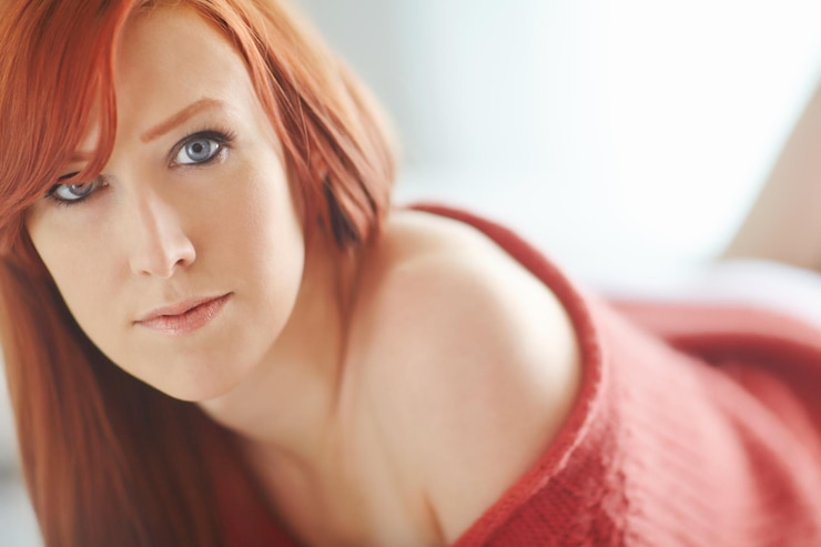 Foto retrato de mulher e ruiva com close-up no quarto com maquiagem para beleza com olhos azuis pela manhã expressão conforto e relaxamento em suéter para o inverno com confiança em casa ou apartamento