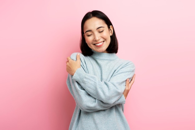 Retrato de mulher egoísta autosatisfeita abraçando-se e sorrindo com prazer