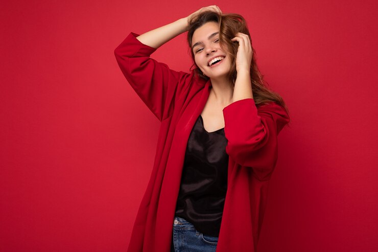 Retrato de mulher elegante alegre positiva em trajes formais, olhando para a câmera isolada no vermelho