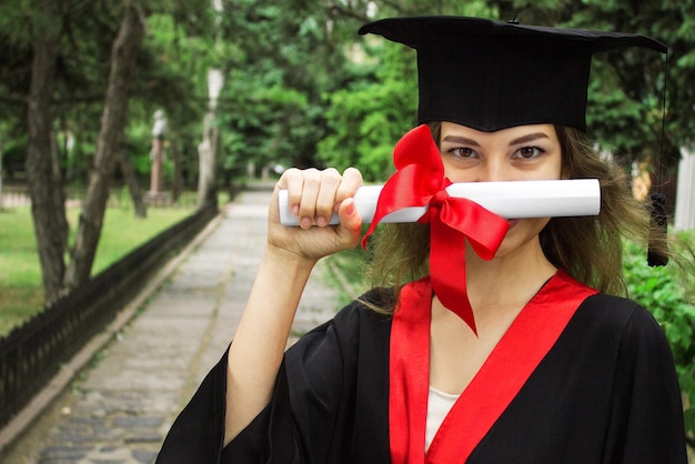 Retrato de mulher em seu dia de formatura, graduação em educação universitária e conceito de pessoas