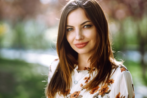 Retrato de mulher em um vestido bonito com flores gosta de florescer jardim verde em dia de primavera. Conceito de moda e estilo.