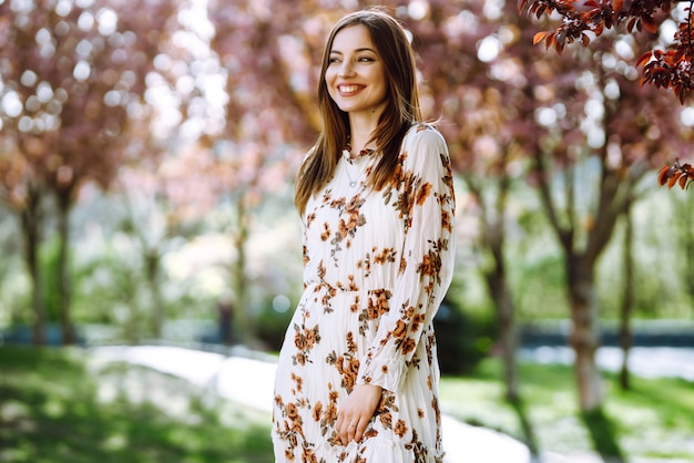 Retrato de mulher em um vestido bonito com flores gosta de florescer jardim verde em dia de primavera. Conceito de moda e estilo.